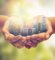 Image showing hands holding city over green natural background