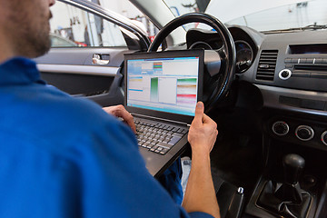 Image showing mechanic man with laptop making car diagnostic