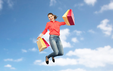 Image showing smiling young woman with shopping bags jumping