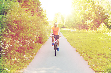 Image showing happy young man riding bicycle outdoors