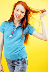 Image showing young pretty red hair teenage hipster girl posing in glasses emotional happy smiling on yellow background, lifestyle people concept 