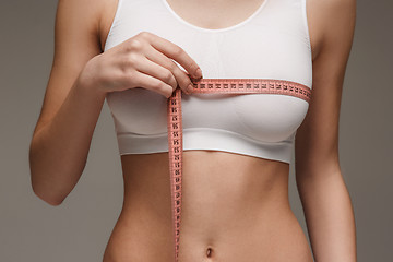 Image showing The girl taking measurements of her body, white background.