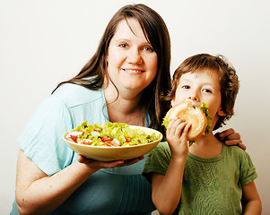 Image showing mature woman holding salad and little cute boy with hamburger te