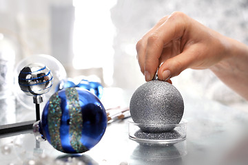 Image showing Work on decorating Christmas baubles. A woman painting a design on a silver bauble Christmas star, Christmas decoration