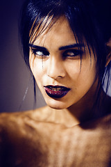 Image showing pretty brunette woman with make up like demon at halloween, closeup scary background