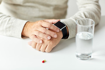 Image showing close up of senior man with water, pill and watch