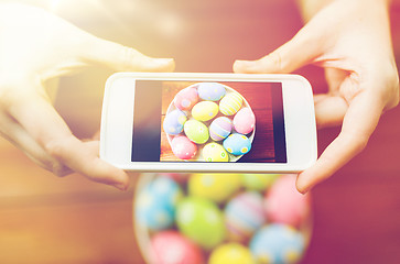 Image showing close up of hands with easter eggs and smartphone