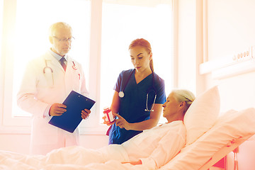 Image showing doctor giving medicine to senior woman at hospital