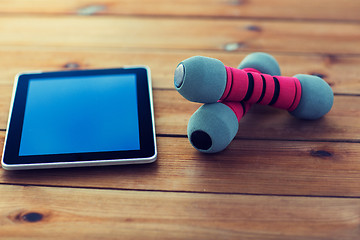 Image showing close up of dumbbells and tablet pc on wood