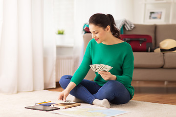 Image showing happy woman with money and travel map at home
