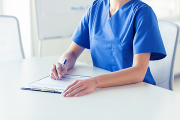 Image showing close up of doctor or nurse writing to clipboard