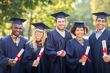 Image showing happy students in mortar boards with diplomas