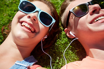 Image showing happy teenage couple with earphones lying on grass