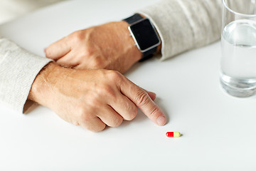 Image showing close up of senior man with water, pill and watch