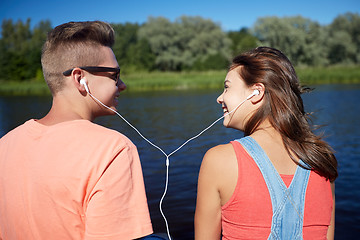 Image showing happy teenage couple with earphones on river berth