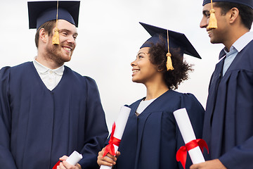 Image showing happy students in mortar boards with diplomas