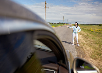 Image showing woman hitchhiking and stopping car with thumbs up