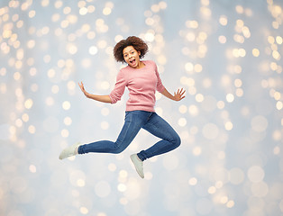 Image showing happy african american woman jumping over white