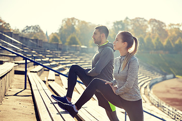 Image showing couple stretching leg on stands of stadium