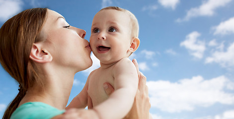 Image showing happy mother kissing little baby over blue sky