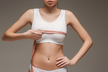 Image showing The girl taking measurements of her body, white background.