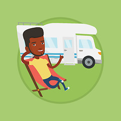 Image showing Man sitting in chair in front of camper van.