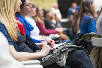 Image showing Hands holding pens and making notes at conference lecture.