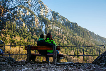 Image showing Couple sitting on bench near mountains