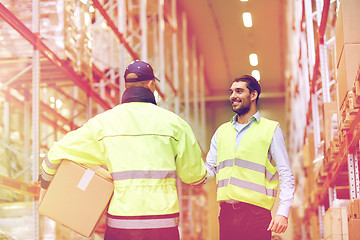 Image showing men in safety vests shaking hands at warehouse