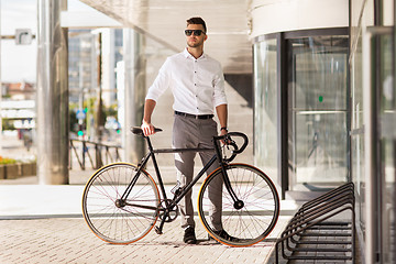 Image showing young man parking his bicycle on city street