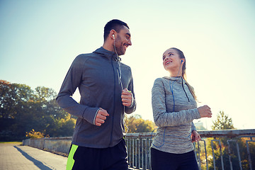 Image showing happy couple with earphones running outdoors