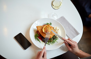 Image showing woman with smartphone eating salad at restaurant