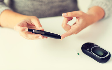 Image showing close up of woman making blood test by glucometer