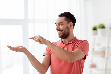 Image showing happy man holding something imaginary at home