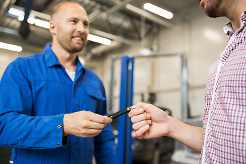 Image showing auto mechanic giving car key to man at workshop