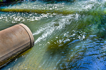 Image showing Water flows from the pipe into the river.