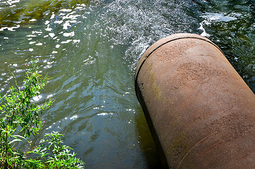 Image showing Water flows from the pipe into the river.