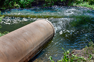 Image showing Water flows from the pipe into the river.