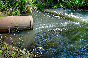 Image showing Water flows from the pipe into the river.