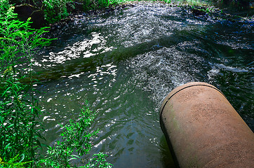 Image showing Water flows from the pipe into the river.