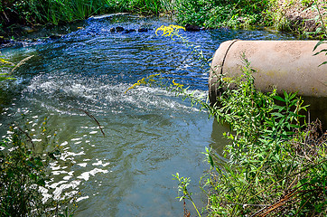 Image showing Water flows from the pipe into the river.