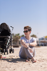 Image showing Young mother with sunglasses relaxing on beach