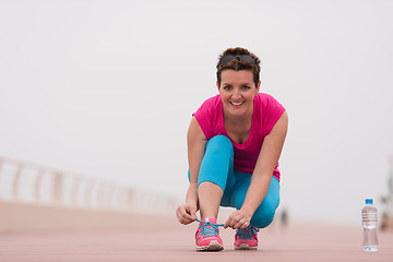 Image showing Young woman tying shoelaces on sneakers