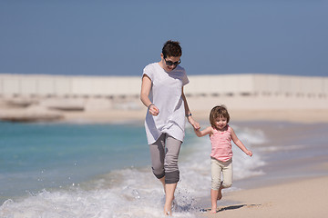 Image showing mother and daughter running on the beach