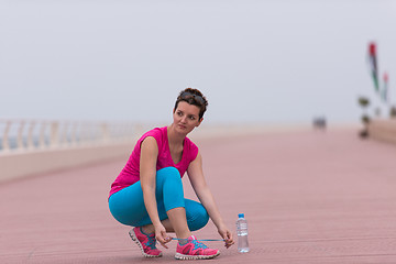 Image showing Young woman tying shoelaces on sneakers