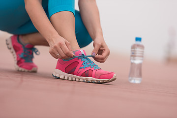 Image showing Young woman tying shoelaces on sneakers