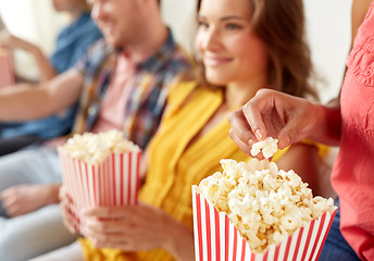 Image showing close up of happy friends eating popcorn at home