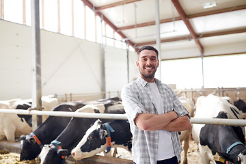 Image showing man or farmer with cows in cowshed on dairy farm