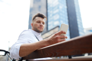 Image showing close up of man texting on smartphone in city