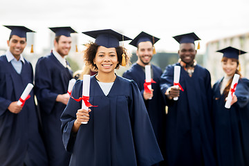 Image showing happy students in mortar boards with diplomas